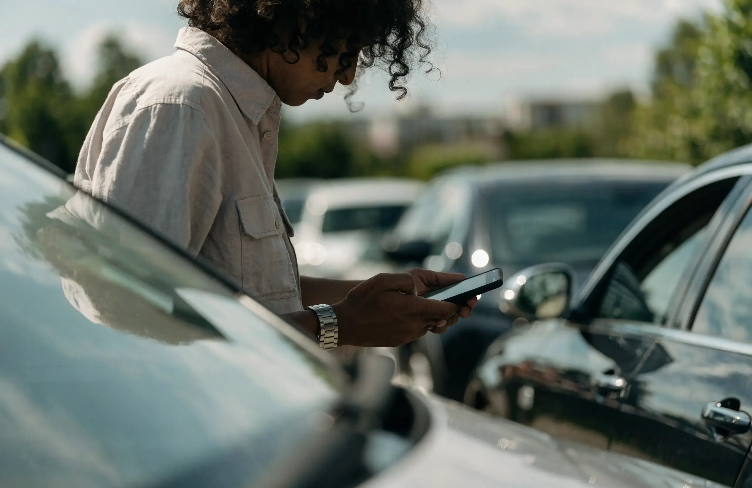 Car buyer browsing vehicles on a smartphone at a dealership