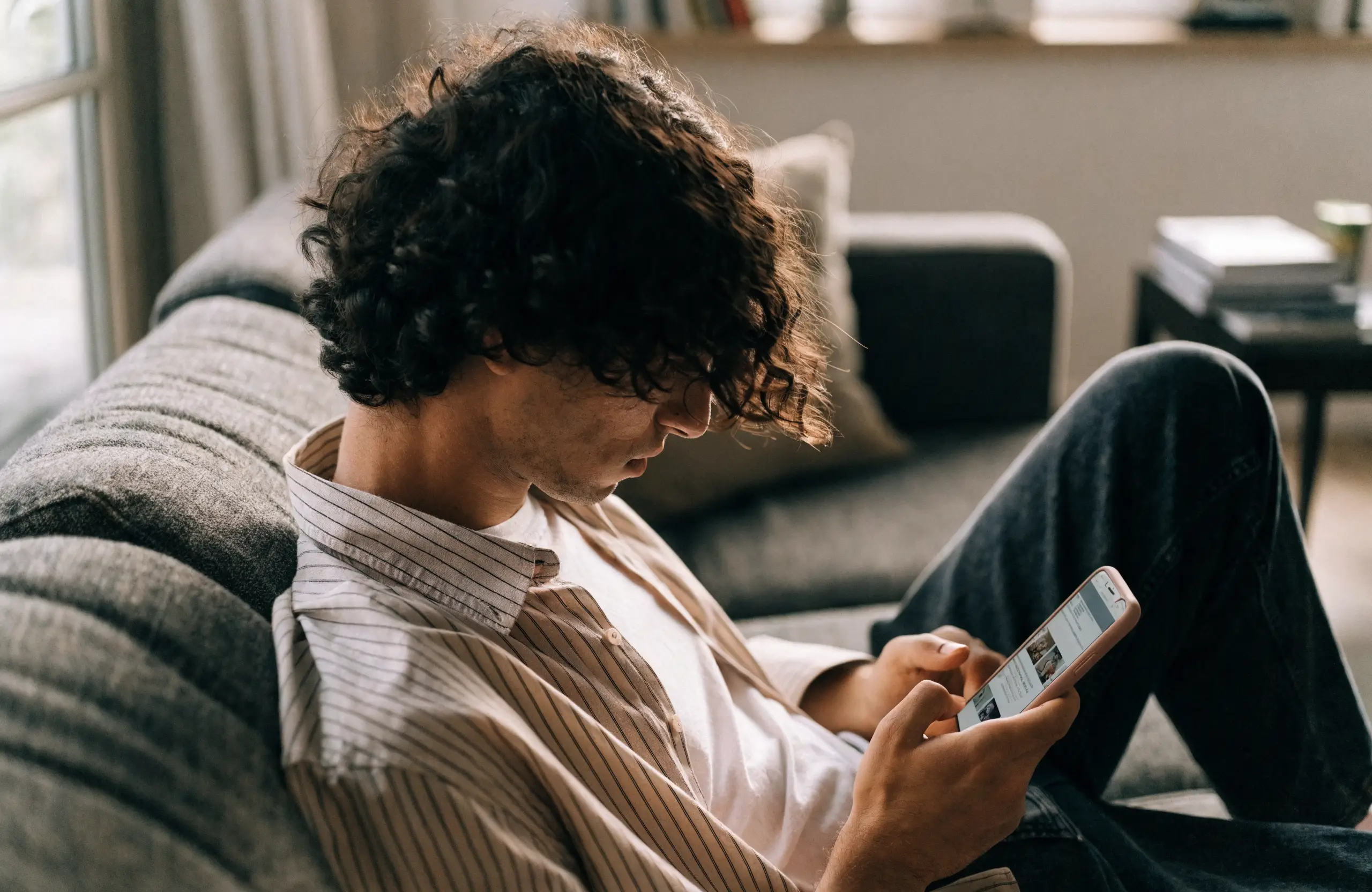 Person scrolling a social media feed on a smartphone at home