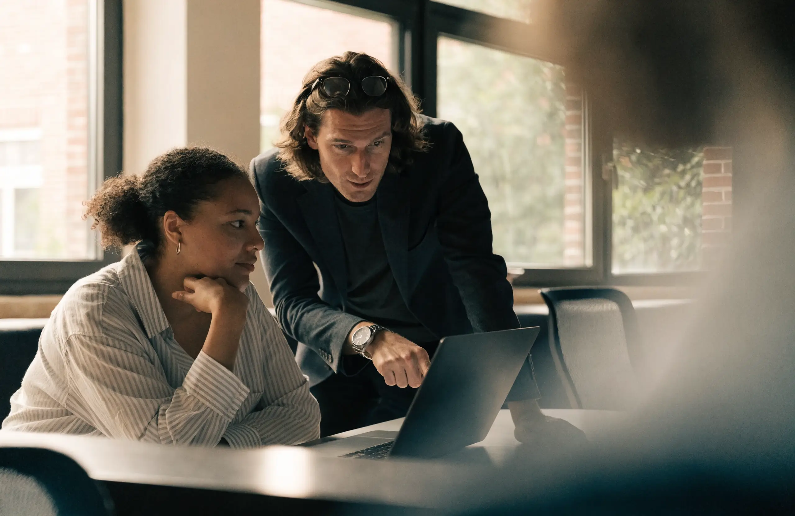 Two colleagues reviewing AI-generated output together on a laptop
