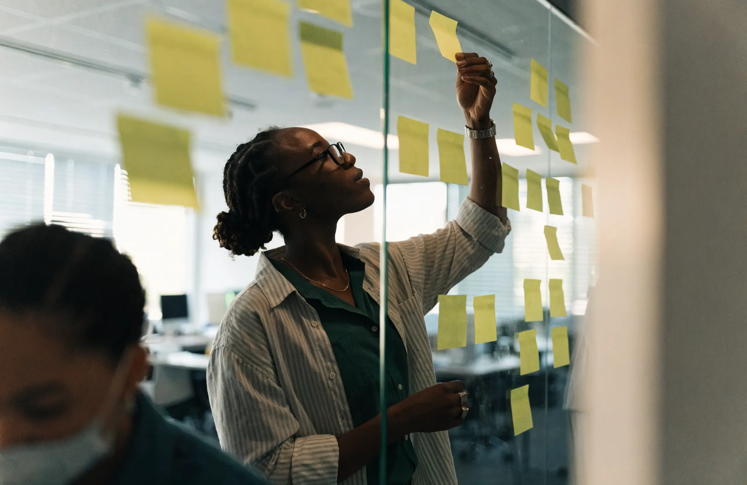 Marketer mapping out a content strategy with sticky notes on a glass wall