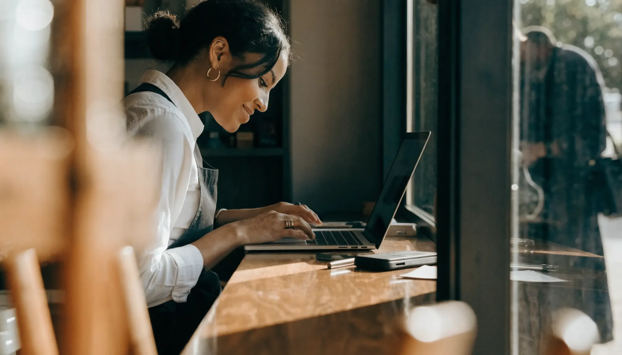 marketing-automation-small-business-owner - Caffeinate Digital Small business owner responding to a customer enquiry on a laptop at her counter